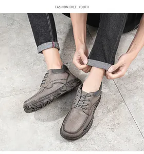 Détail de bottes Martin en cuir pour hommes avec coutures faites main sur carrelage gris