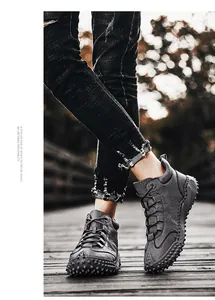Close-up of men's grey textured leather high-top outdoor hiking boots with studded sole