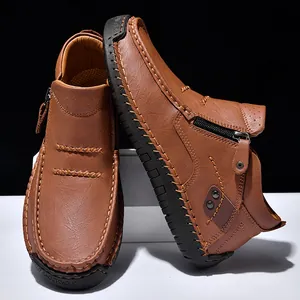 Dettaglio scarpe da uomo in pelle marrone con cerniera e cuciture fatte a mano.