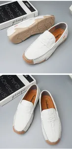 Detailed view of white textured leather loafers for men with tan rubber soles.