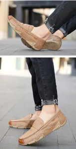 Detail of men's tan cowhide leather loafers worn on street with casual black jeans