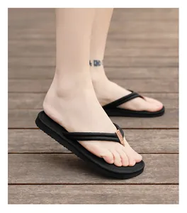 Detailansicht der schwarzen Herren-Flip-Flops mit dicker Sohle auf Holzterrasse.