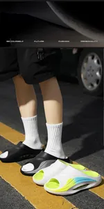 Detailed view of trendy men's outdoor slides in black and gradient white colors on street pavement