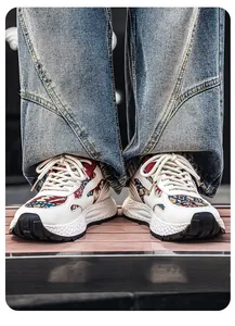 Nahaufnahme von weißen Chunky-Sneakern mit bunten Mustern und Denim-Jeans