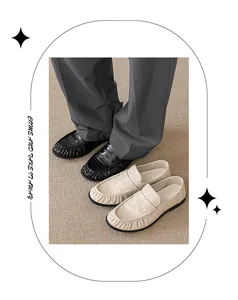 Close-up detail of textured cream and black designer slip-on loafers on neutral carpet