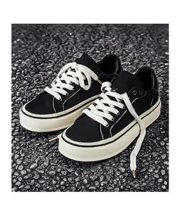 Detail view of black canvas sneakers with thick white rubber soles on gravel surface.