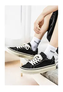 Detail view of black canvas sneakers with thick soles and white laces for men.