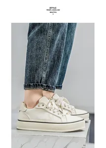 Detail view of trendy white canvas platform sneakers for men worn with cuffed denim jeans