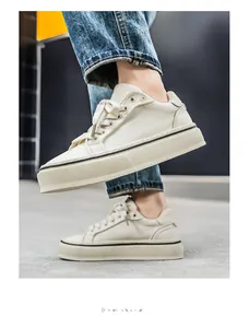 Side view of stylish cream canvas men's sneakers with thick soles worn with denim jeans