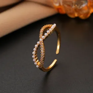 Detail of gold infinity ring with small pearls and crystals on dark textured ground