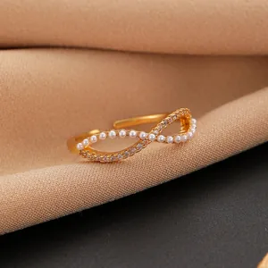 Close-up of infinity gold ring with pearls and crystals on beige fabric background