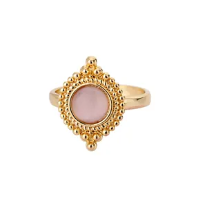 Close-up of gold-plated vintage ring featuring a central pink stone and beaded detail
