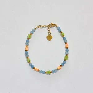 Detail view of a colorful beaded bracelet with faceted stones and a gold heart charm