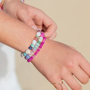 Detailed close-up showing colorful natural stone and pearl beaded bracelets worn on a wrist
