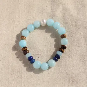 Detailed view of a colorful natural stone beaded bracelet with pearl on a linen background