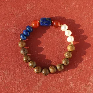 Detail of a colorful beaded bracelet with natural stones, pearls, and wood on red background.