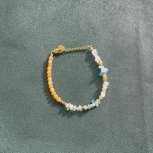 Detail showing candy-colored natural stone beads and gold heart charm on a bracelet.