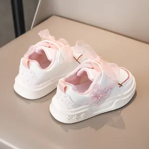 Vista dettagliata di sneaker bianche da bambina con fiocchi in pizzo e farfalle.