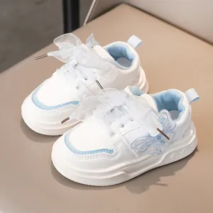 Dettaglio di sneaker bianche da bambina con farfalla blu e lacci a fiocco in organza.