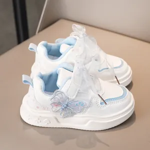 Dettaglio scarpe da ginnastica bianche da bambina con farfalla di paillettes e fiocco