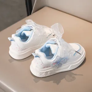Primo piano di scarpe bianche da bambina con farfalla blu chiaro e fiocco in mesh