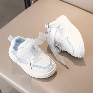 Dettaglio scarpe da ginnastica bianche per bambina con ricamo farfalla blu e lacci a nastro