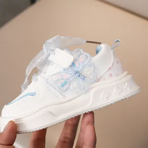 Dettaglio scarpa sportiva bianca per bambina con farfalla blu e lacci in nastro