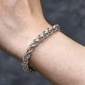 Primo piano di un bracciale a catena di grano in acciaio inossidabile lucido al polso