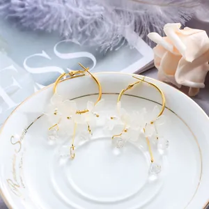 Detail of elegant gold hoop earrings with translucent white flower petals and crystals