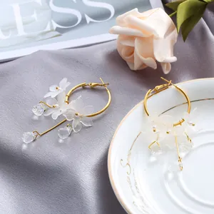 Detailed view of elegant gold hoop earrings with white frosted petals and crystal drops