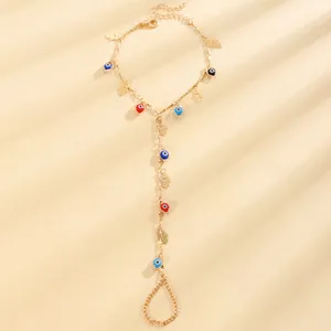 Detailed view of a gold hand harness featuring colorful evil eye beads and hamsa pendants