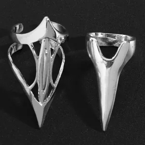 Detailed view of two punk style silver pointed metal nail rings on black background