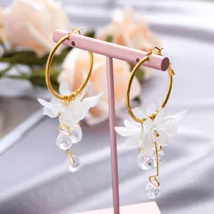Detailed macro view of elegant gold hoop earrings with white petals and crystal drops