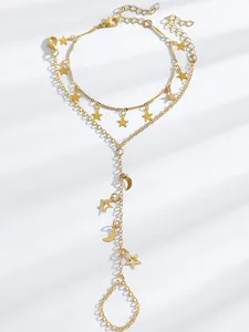 Close-up detail of a gold-toned chain hand harness featuring star and moon charm dangles