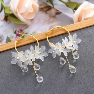 Elegant gold hoop earrings with frosted white floral petals and clear crystal charms