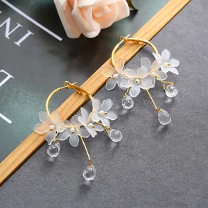 Detailed macro view of elegant floral hoop earrings with frosted petals and crystal drops.