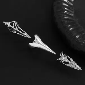 Close-up of three different silver metal gothic nail claw rings on a dark surface.