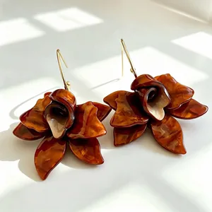 Detailed macro view of tortoiseshell resin flower petal earrings with gold hooks