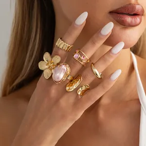 Close-up view of gold liquid lava rings with flower and pink pearl details on hand