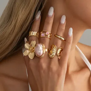 Detailed view of elegant gold flower and pink pearl rings set on a model's hand.