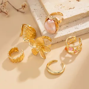 Detailed macro view of vintage gold ring set featuring liquid lava and baroque pearl designs.