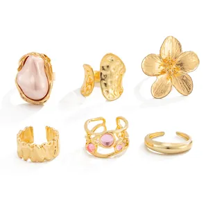 Close-up of diverse gold ring collection featuring lava, flower, and faux pearl designs.