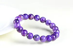 Détail macro d'un bracelet en perles de charoïte violette naturelle sur fond blanc