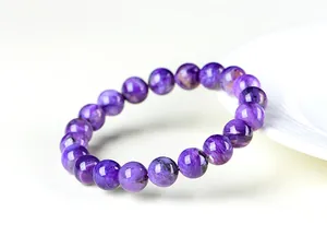 Gros plan détaillé d'un bracelet en perles de charoïte violette naturelle sur une assiette