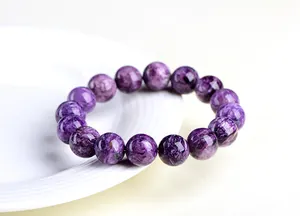Vue détaillée d'un bracelet en pierre de charoïte violette sur assiette blanche