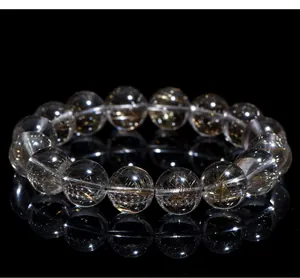 Close-up of natural silver rutilated quartz bead bracelet on a reflective black base