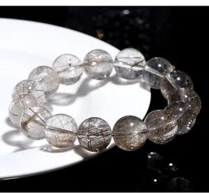 Macro view of natural silver rutilated quartz beaded bracelet on white porcelain plate