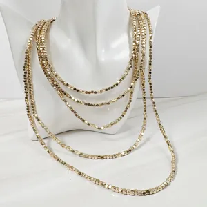 Detalle de un collar dorado de varias capas con pequeñas cuentas en forma de cubo