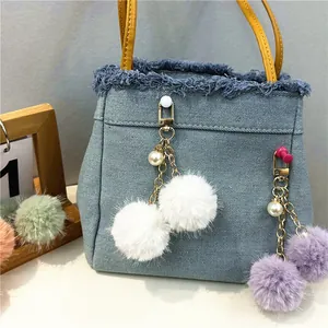 Primer plano de colgantes de bolas de peluche blancos y morados con perlas en bolso