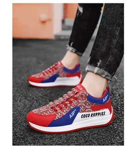 Close-up detail of men's casual red and blue canvas sneakers worn on an asphalt road